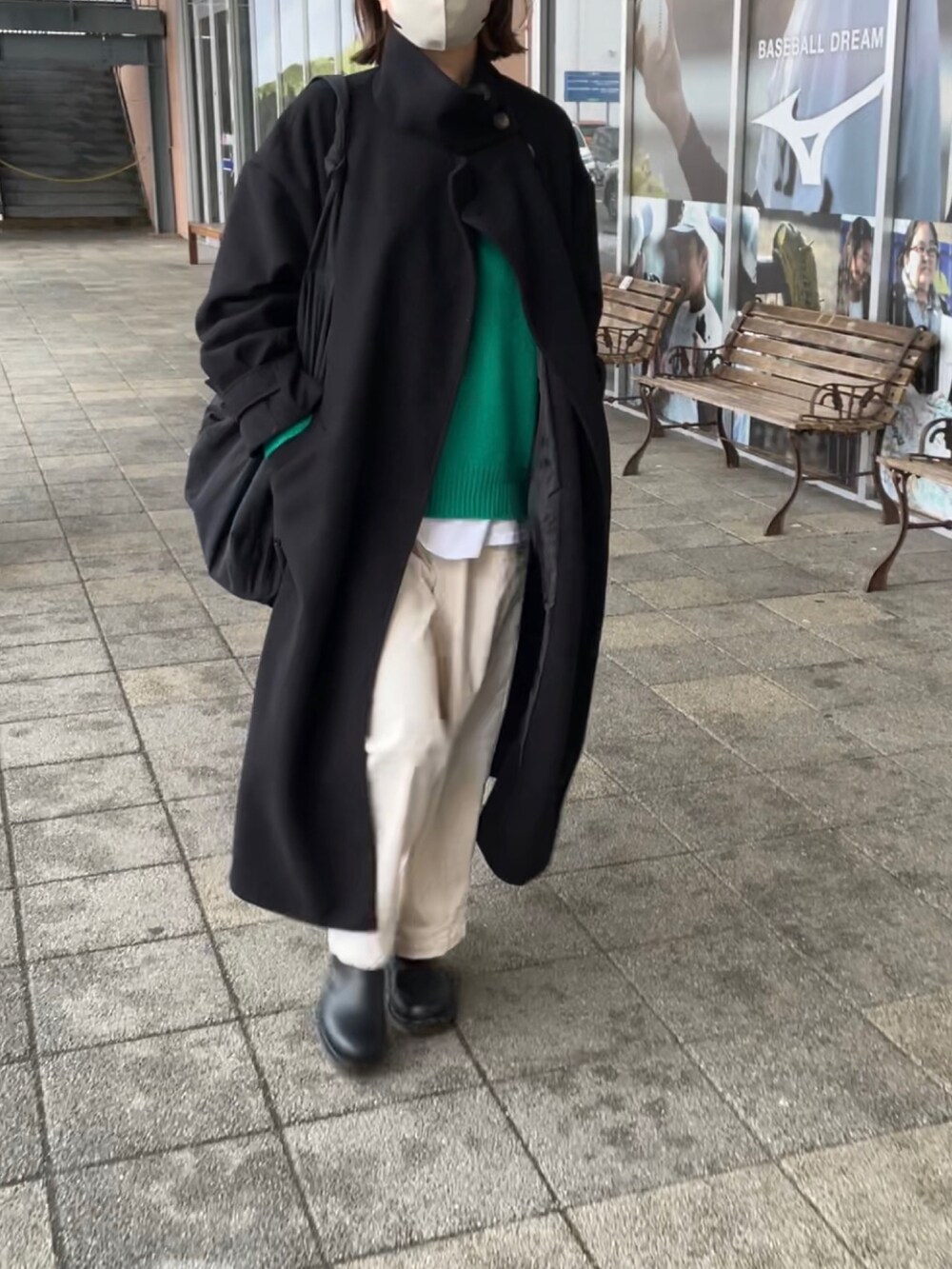 ブラック系のトレンチコート、グリーン系のニット/セーター、ホワイト系のパンツを着用したレディースの冬コーディネートの2枚目の写真