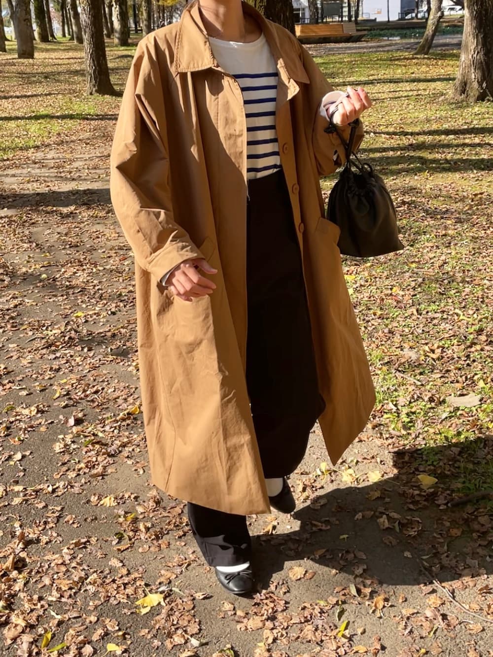 ベージュ系のステンカラーコート、その他のTシャツ/カットソー、ブラック系のパンツを着用したレディースの秋コーディネートの2枚目の写真