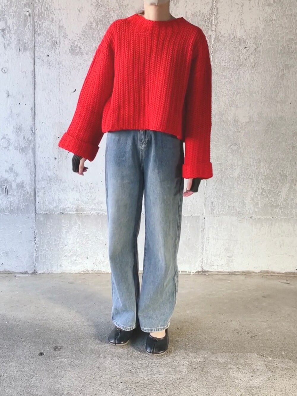 レッド系のニット/セーター、ブルー系のデニムパンツ、グレー系のアームカバーを着用したレディースの冬コーディネートの3枚目の写真