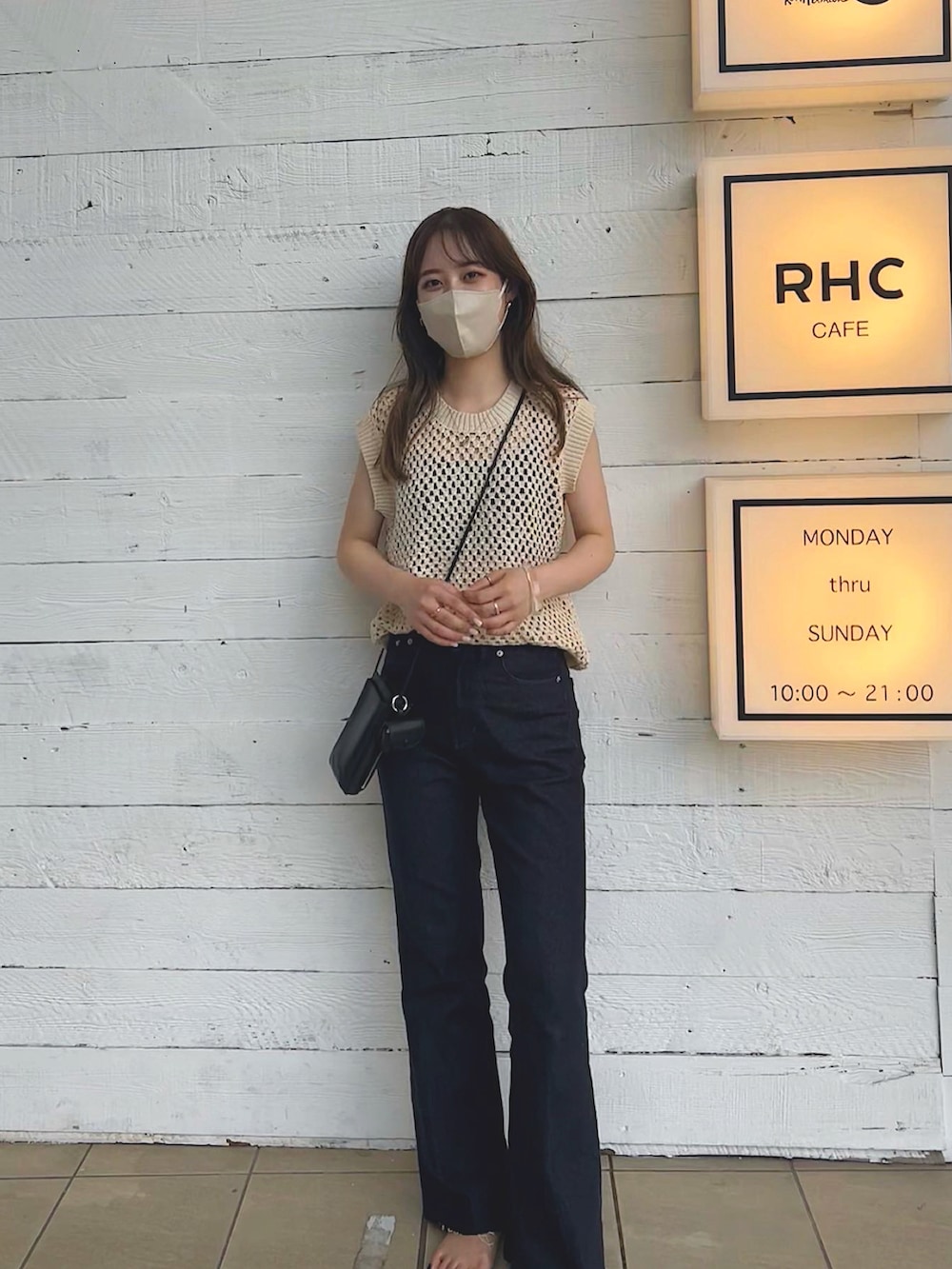 ブルー系のデニムパンツ、ベージュ系のベスト、ブラック系のショルダーバッグを着用したレディースの夏コーディネートの2枚目の写真