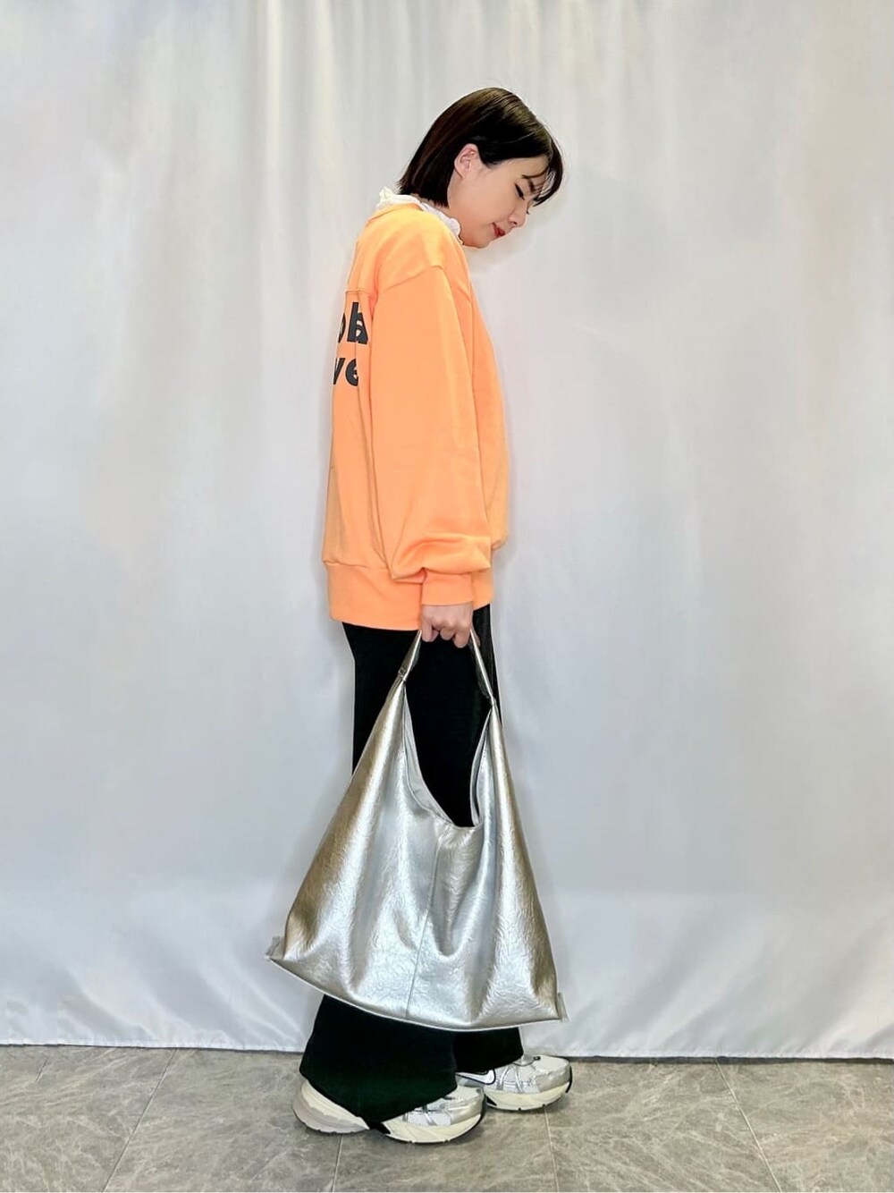 オレンジ系のスウェット、ホワイト系のTシャツ/カットソー、ブラック系のその他パンツを着用したレディースの冬コーディネートの2枚目の写真
