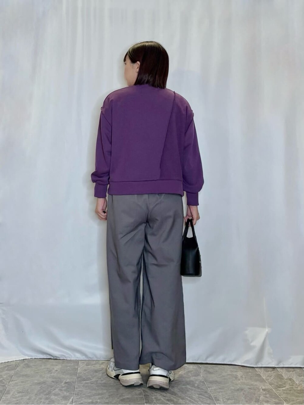 パープル系のスウェット、グレー系のその他パンツ、ブラック系のショルダーバッグを着用したレディースの秋コーディネートの3枚目の写真