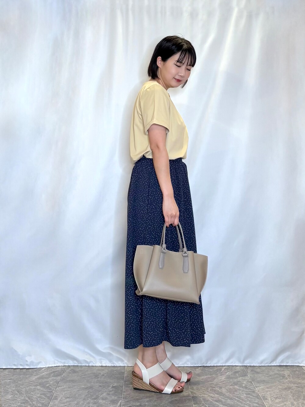 イエロー系のシャツ/ブラウス、ブルー系のスカート、ホワイト系のサンダルを着用したレディースの春コーディネートの2枚目の写真