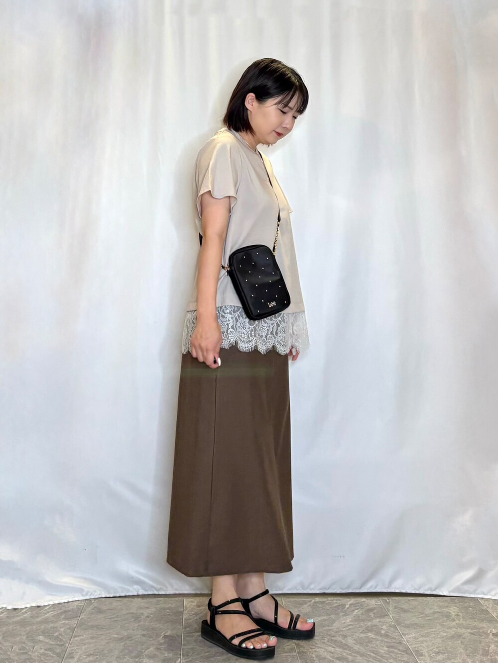 ベージュ系のシャツ/ブラウス、ブラウン系のスカート、ブラック系のサンダルを着用したレディースの夏コーディネートの3枚目の写真
