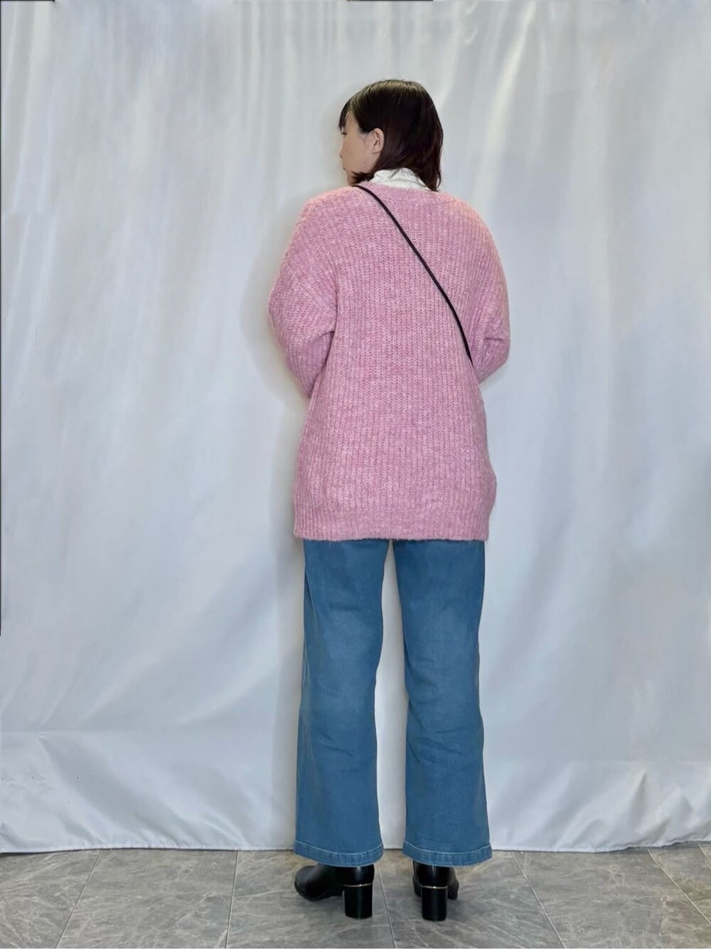 ピンク系のチュニック、ホワイト系のチュニック、ブルー系のデニムパンツを着用したレディースの冬コーディネートの3枚目の写真