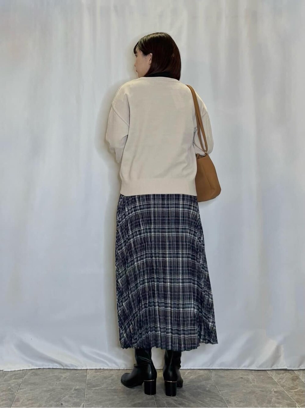 ベージュ系のニット/セーター、ブラック系のTシャツ/カットソー、ブルー系のスカートを着用したレディースの秋コーディネートの3枚目の写真