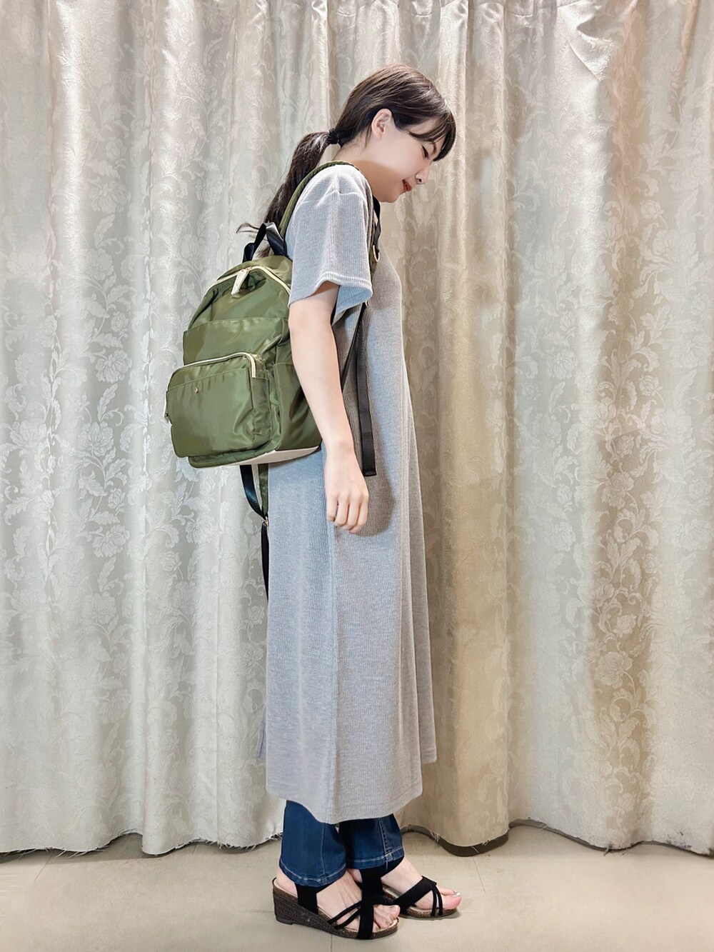グリーン系のバックパック/リュック、ブラック系のサンダル、ブルー系のデニムパンツを着用したレディースの春コーディネートの2枚目の写真
