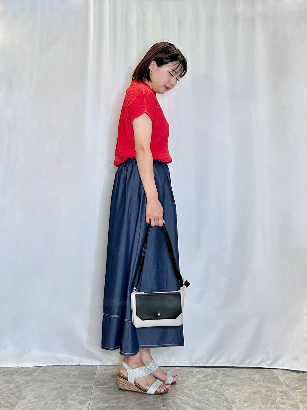 レッド系のTシャツ/カットソー、ブルー系のスカート、シルバー系のサンダルを着用したレディースの夏コーディネートの2枚目の写真
