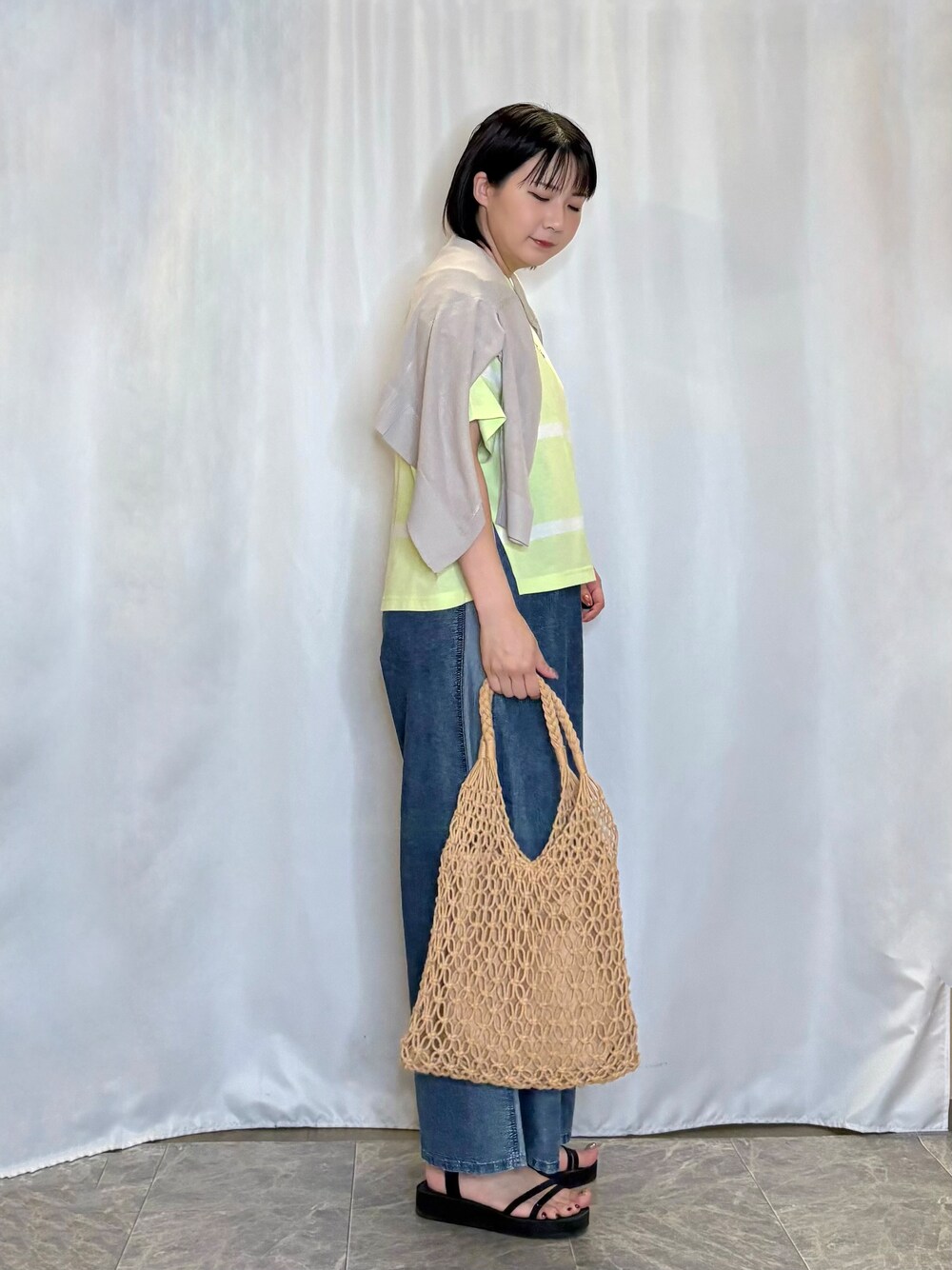 ベージュ系のカーディガン/ボレロ、イエロー系のトートバッグ、ブラック系のサンダルを着用したレディースの春コーディネートの2枚目の写真