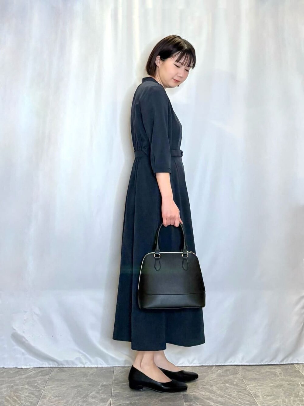 ブラック系のトートバッグ、ブラック系のパンプス、ブルー系のワンピースを着用したレディースの春コーディネートの2枚目の写真