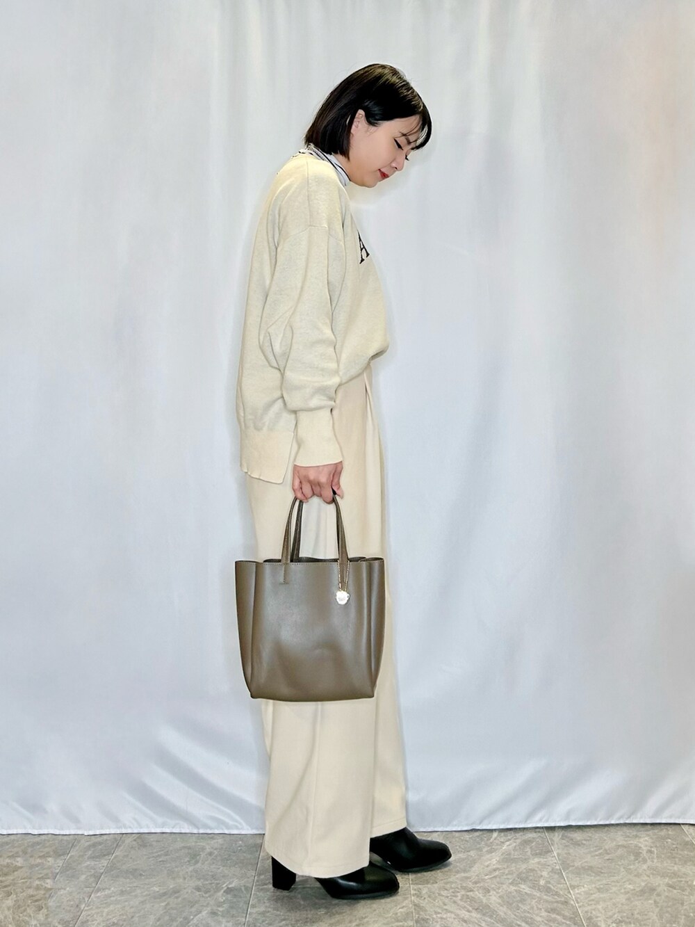 ホワイト系のTシャツ/カットソー、ホワイト系のニット/セーター、ブラック系のブーツを着用したレディースの冬コーディネートの2枚目の写真