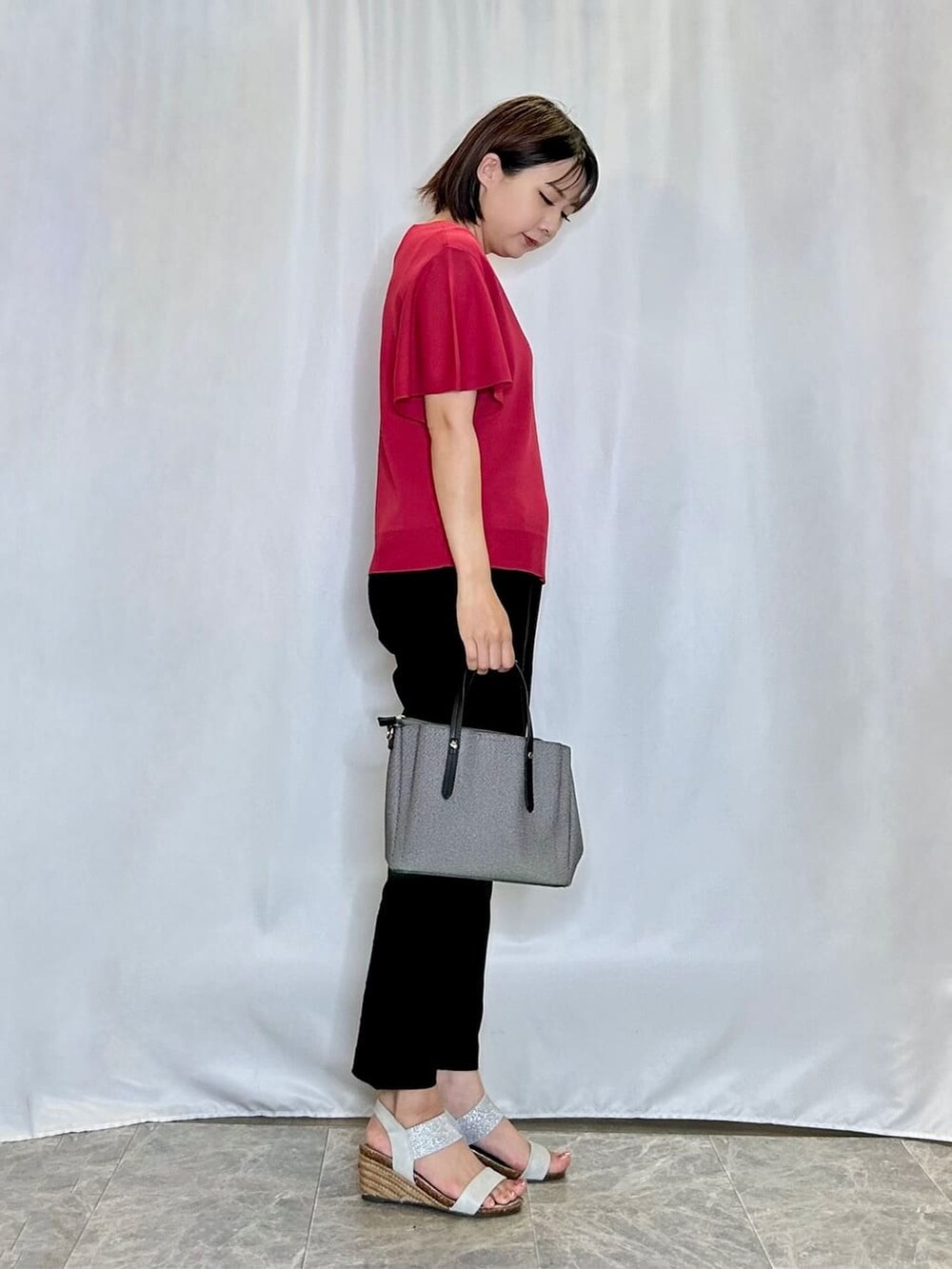 レッド系のニット/セーター、ブラック系のその他パンツ、シルバー系のサンダルを着用したレディースの夏コーディネートの2枚目の写真
