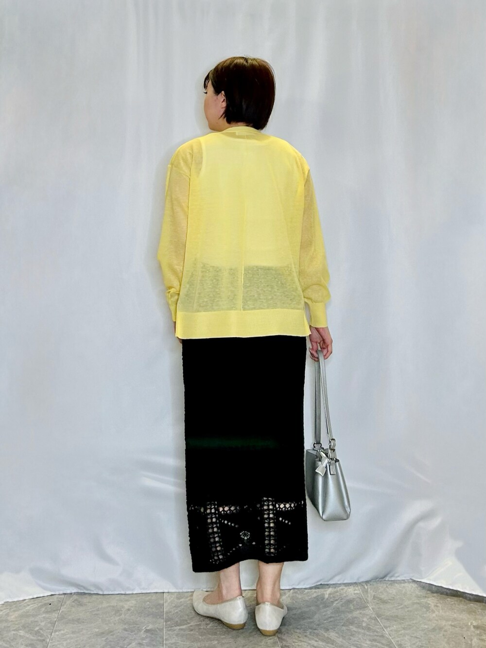 ブラック系のスカート、ゴールド系のその他シューズ、シルバー系のショルダーバッグを着用したレディースの春コーディネートの3枚目の写真