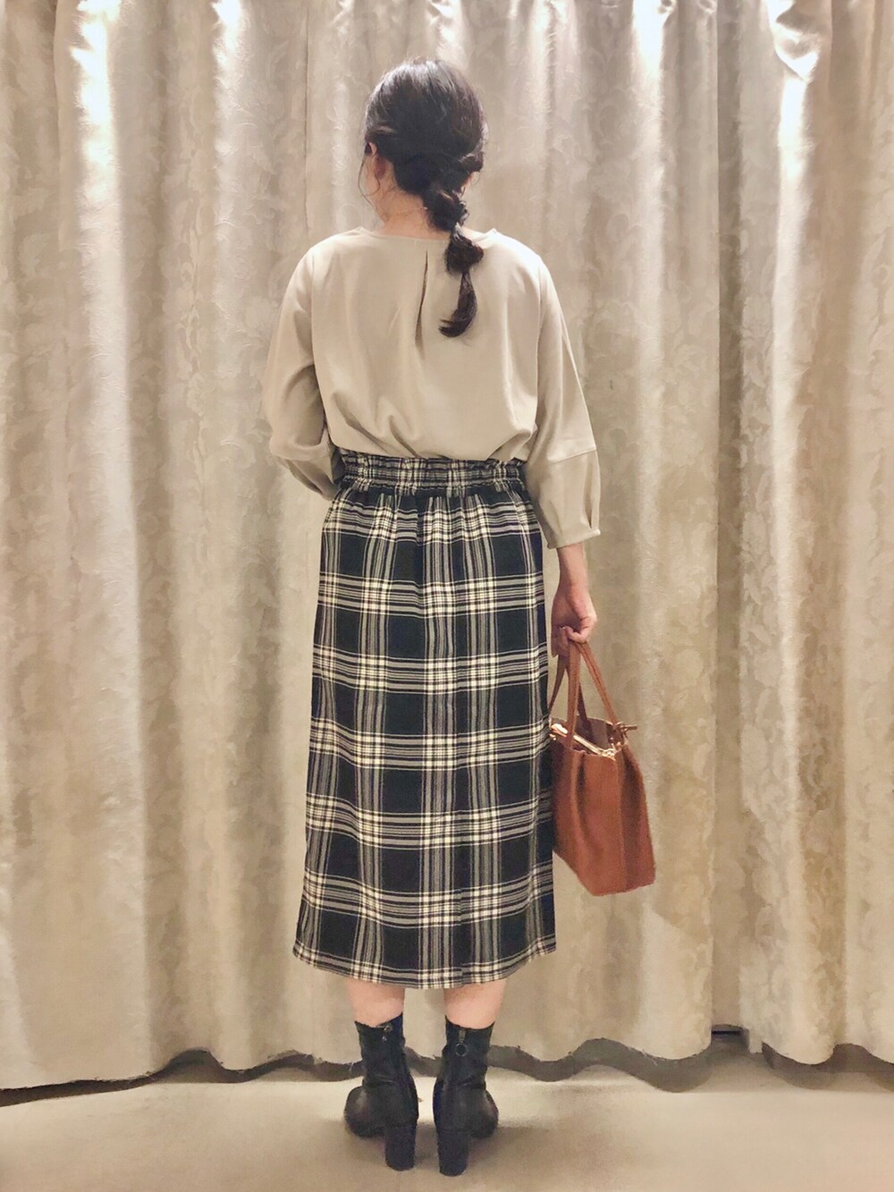 ブラック系のスカート、イエロー系のトートバッグ、ブラック系のブーツを着用したレディースの秋コーディネートの3枚目の写真