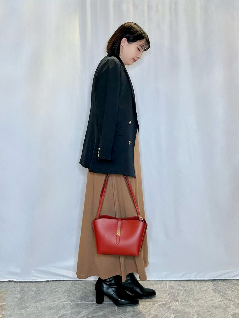 ブルー系のテーラードジャケット、レッド系のショルダーバッグ、ブラック系のブーツを着用したレディースの秋コーディネートの2枚目の写真