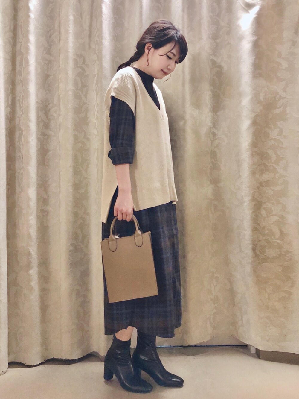 ベージュ系のショルダーバッグ、ブラック系のブーツ、ベージュ系のベストを着用したレディースの秋コーディネートの2枚目の写真