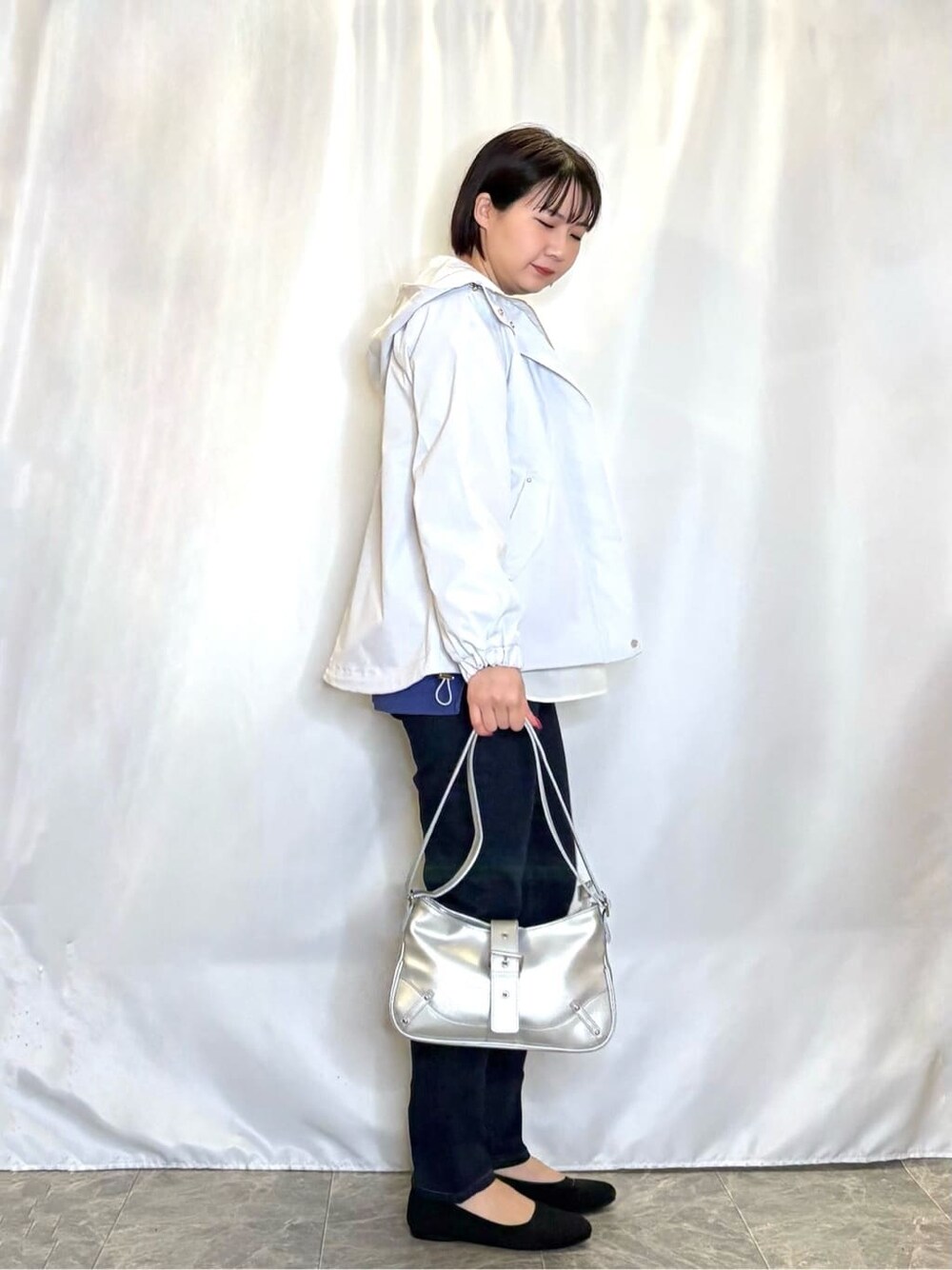 グレー系のブルゾン、パープル系のニット/セーター、ブルー系のデニムパンツを着用したレディースの春コーディネートの2枚目の写真