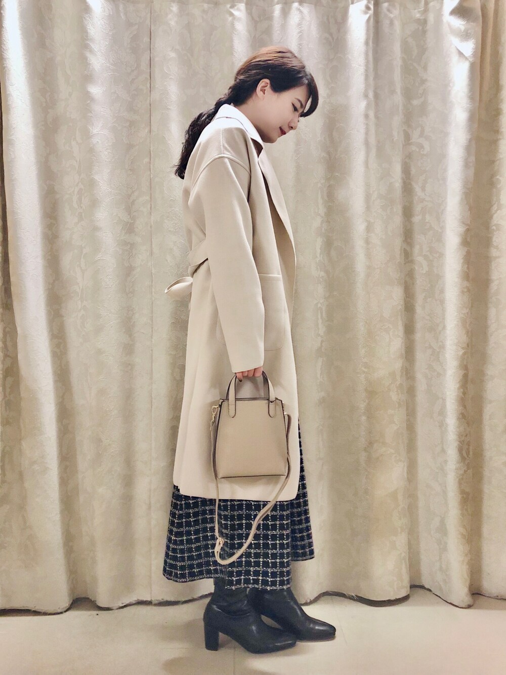 ベージュ系のショルダーバッグ、ブラック系のブーツ、ベージュ系のチェスターコートを着用したレディースの冬コーディネートの2枚目の写真