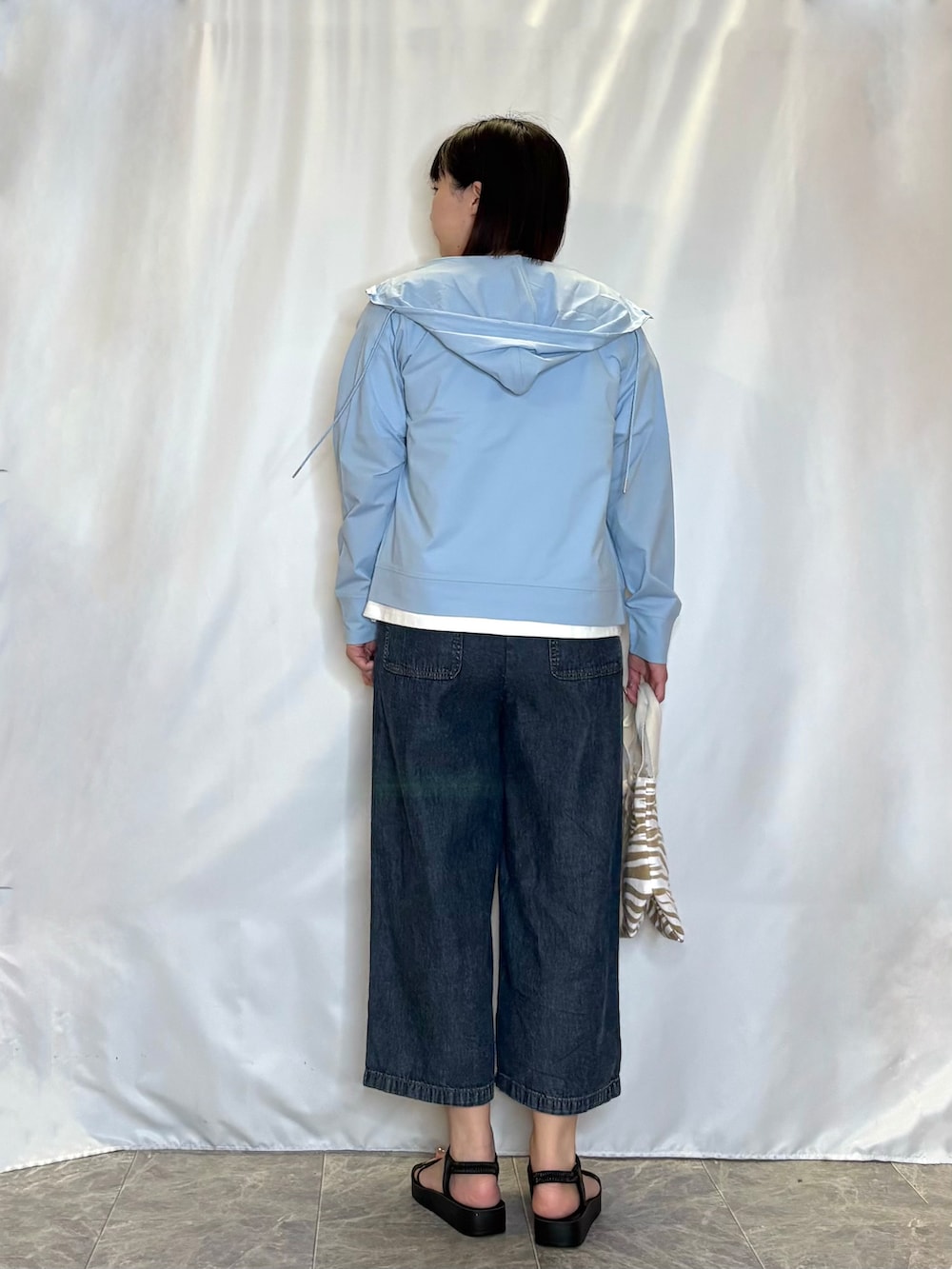 ブルー系のパーカー、ホワイト系のTシャツ/カットソー、ブルー系のデニムパンツを着用したレディースの春コーディネートの3枚目の写真