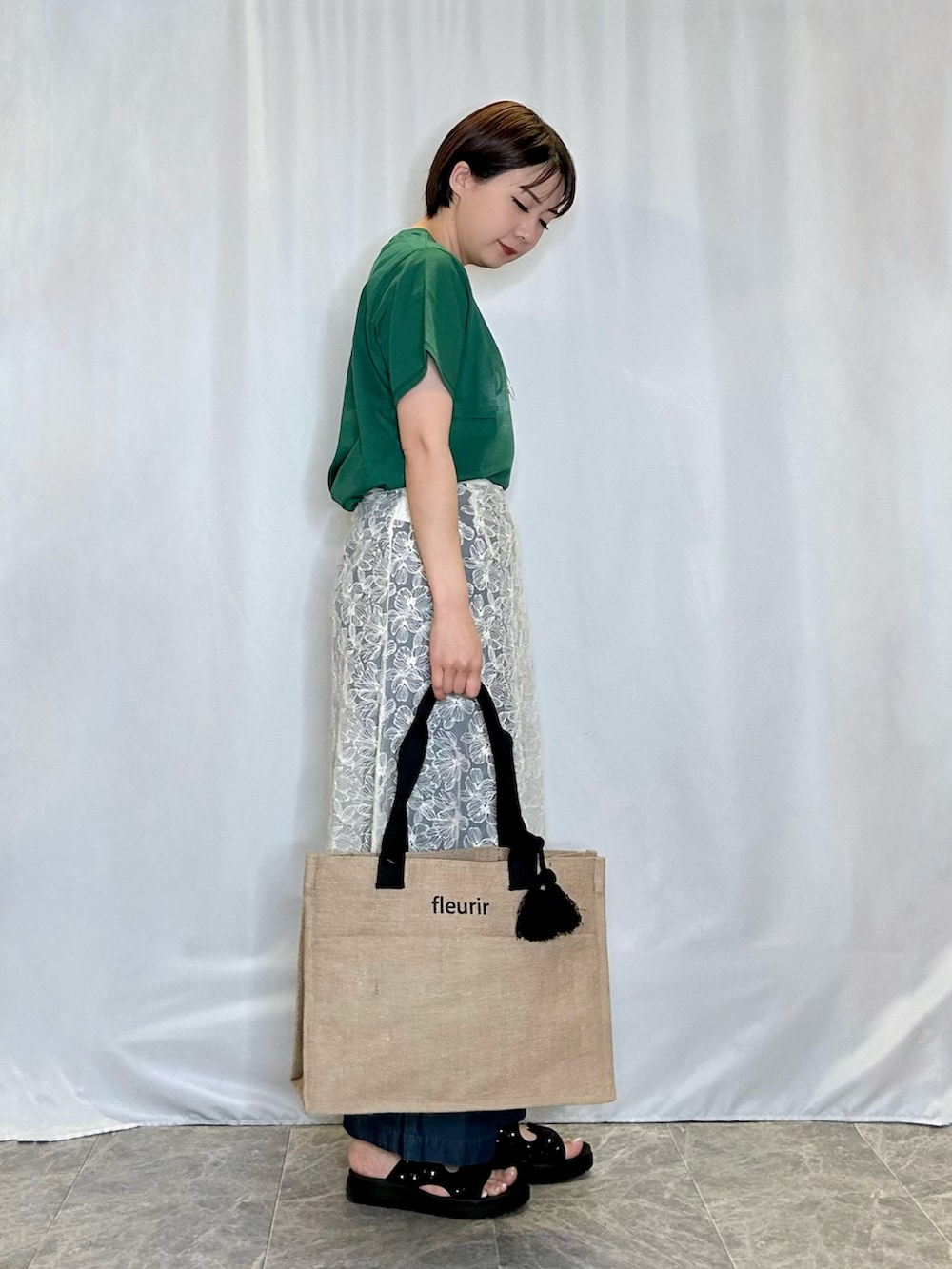 グリーン系のTシャツ/カットソー、ホワイト系のスカート、ブラック系のサンダルを着用したレディースの春コーディネートの2枚目の写真