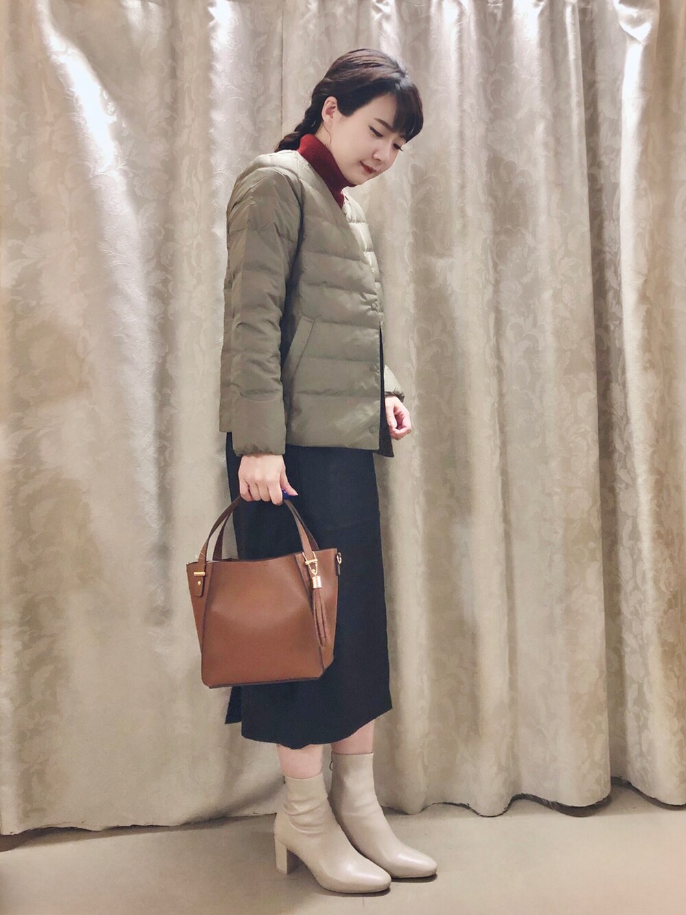 グリーン系のダウンジャケット/コート、ブラック系のスカート、イエロー系のショルダーバッグを着用したレディースの秋コーディネートの2枚目の写真