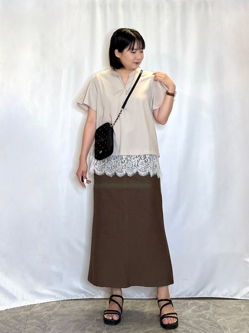 ベージュ系のシャツ/ブラウス、ブラウン系のスカート、ブラック系のサンダルを着用したレディースの夏コーディネートの2枚目の写真