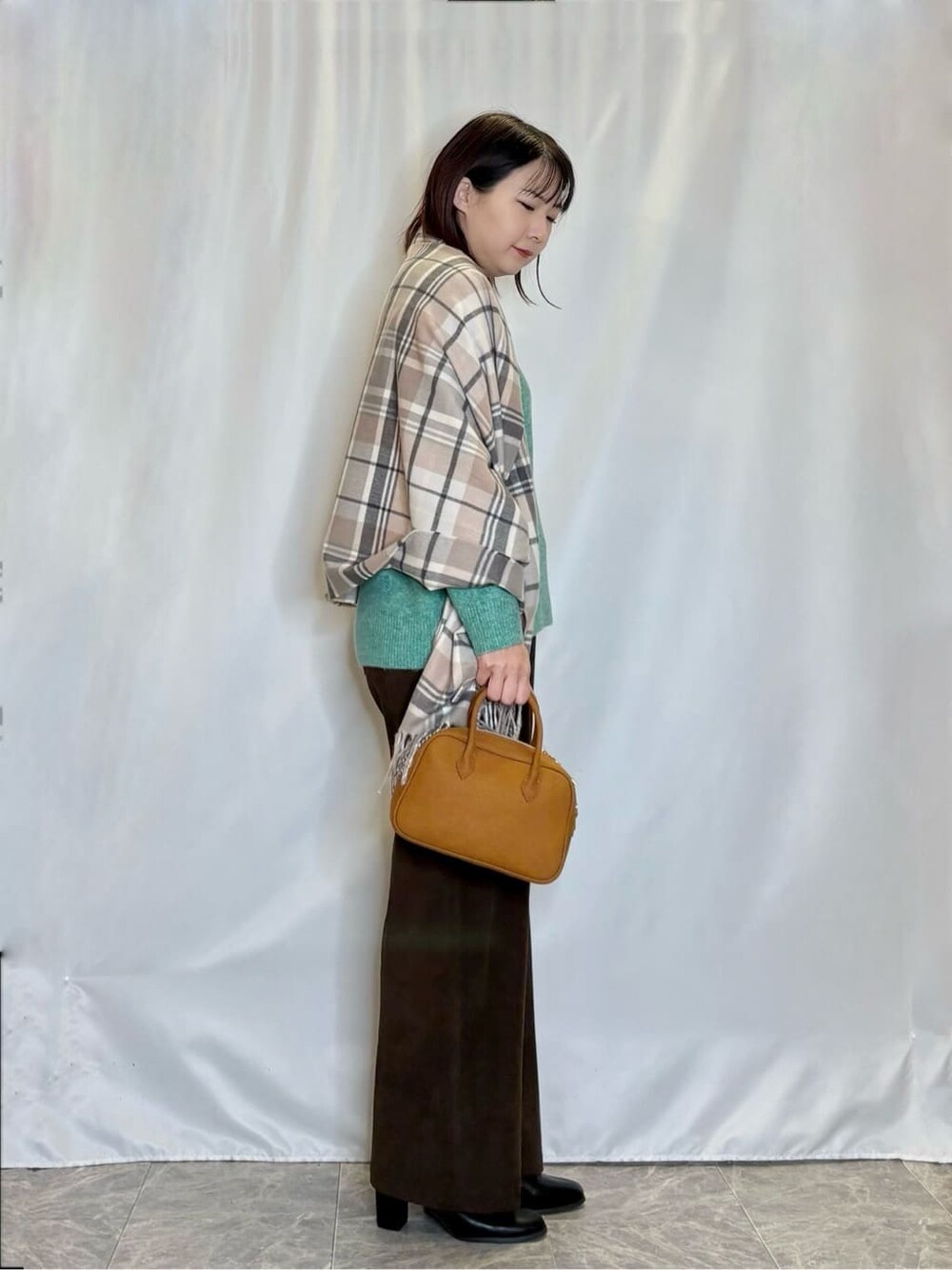 グリーン系のニット/セーター、ブラウン系のその他パンツ、ブラック系のブーツを着用したレディースの冬コーディネートの2枚目の写真
