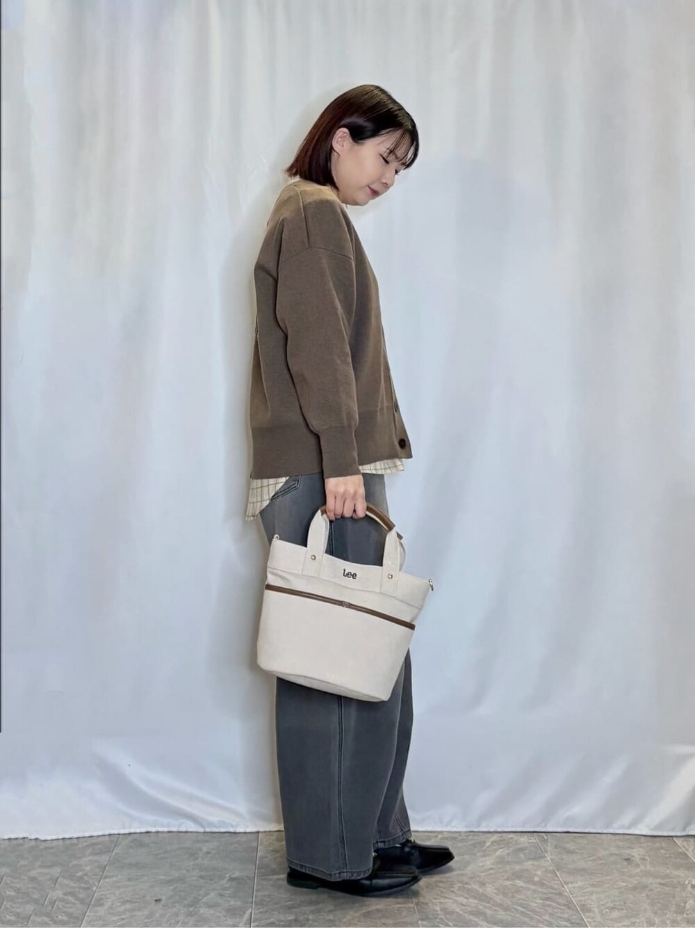 ブラウン系のカーディガン/ボレロ、ベージュ系のシャツ/ブラウス、ブラック系のデニムパンツを着用したレディースの秋コーディネートの2枚目の写真
