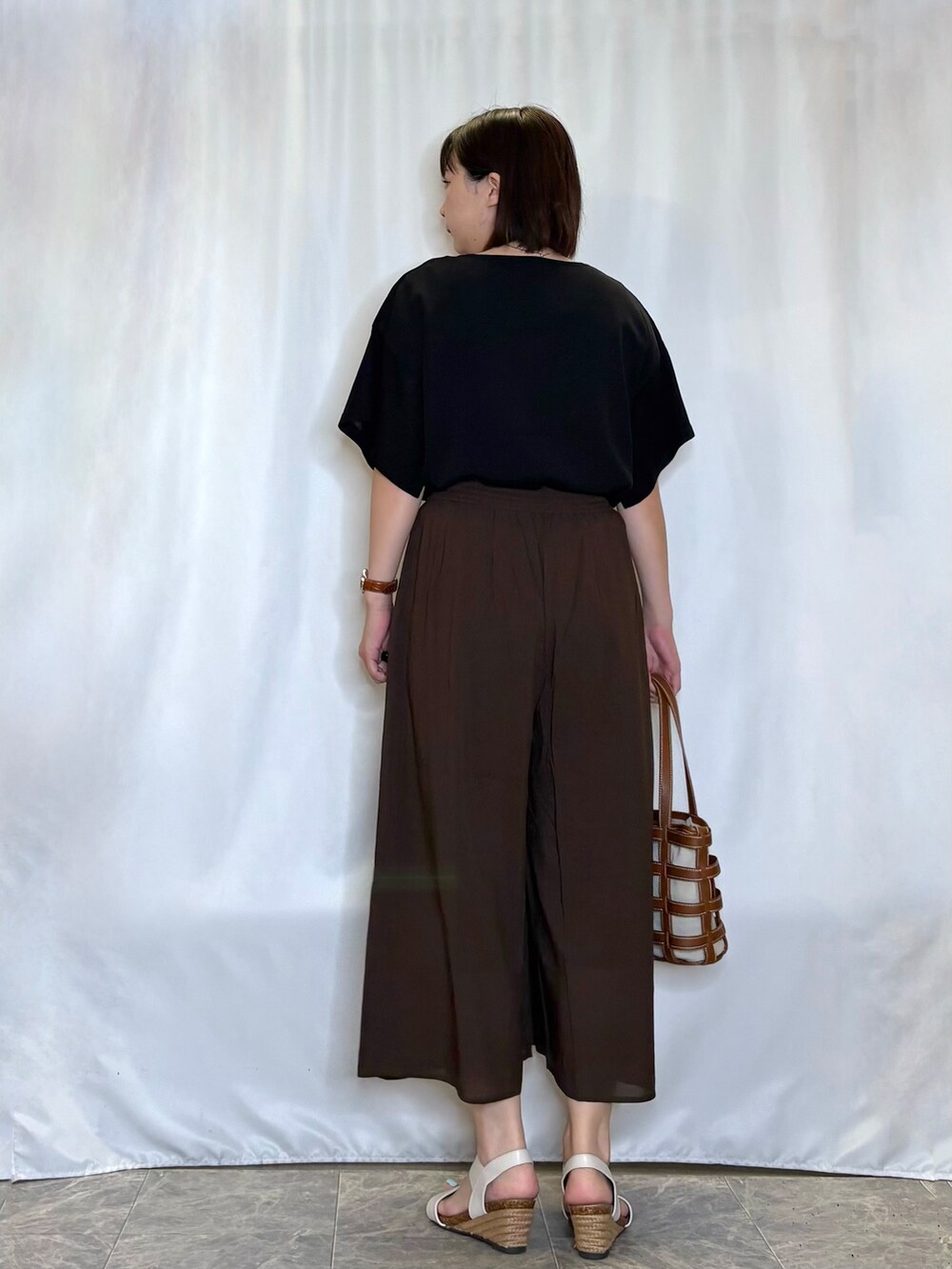 ブラック系のニット/セーター、ブラウン系のその他パンツ、ホワイト系のサンダルを着用したレディースの夏コーディネートの5枚目の写真