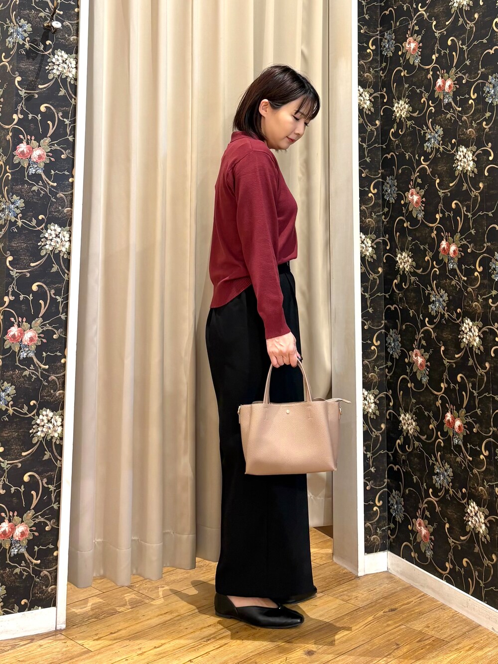 レッド系のニット/セーター、ブラック系のその他パンツ、ベージュ系のトートバッグを着用したレディースの秋コーディネートの2枚目の写真