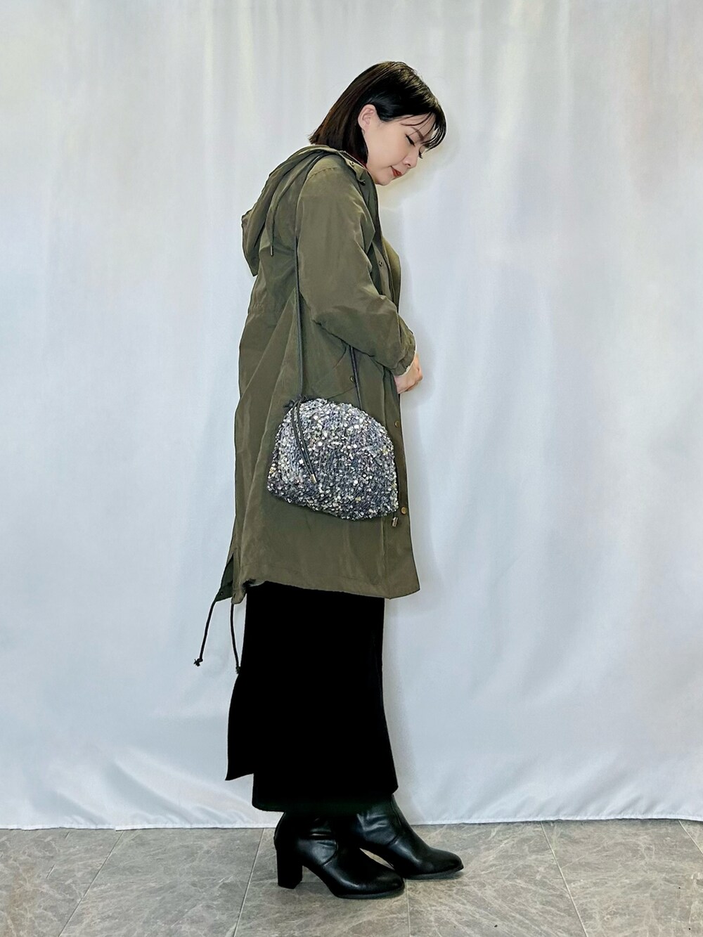 レッド系のニット/セーター、ホワイト系のカーディガン/ボレロ、グリーン系のその他アウターを着用したレディースの冬コーディネートの2枚目の写真