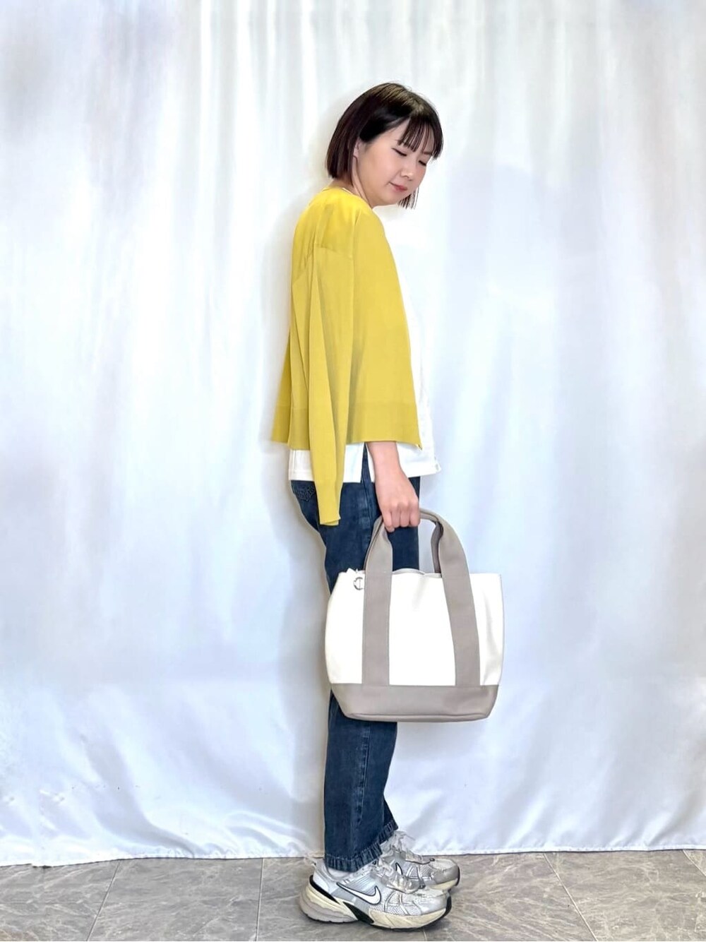 イエロー系のカーディガン/ボレロ、ホワイト系のTシャツ/カットソー、ブルー系のデニムパンツを着用したレディースの春コーディネートの2枚目の写真