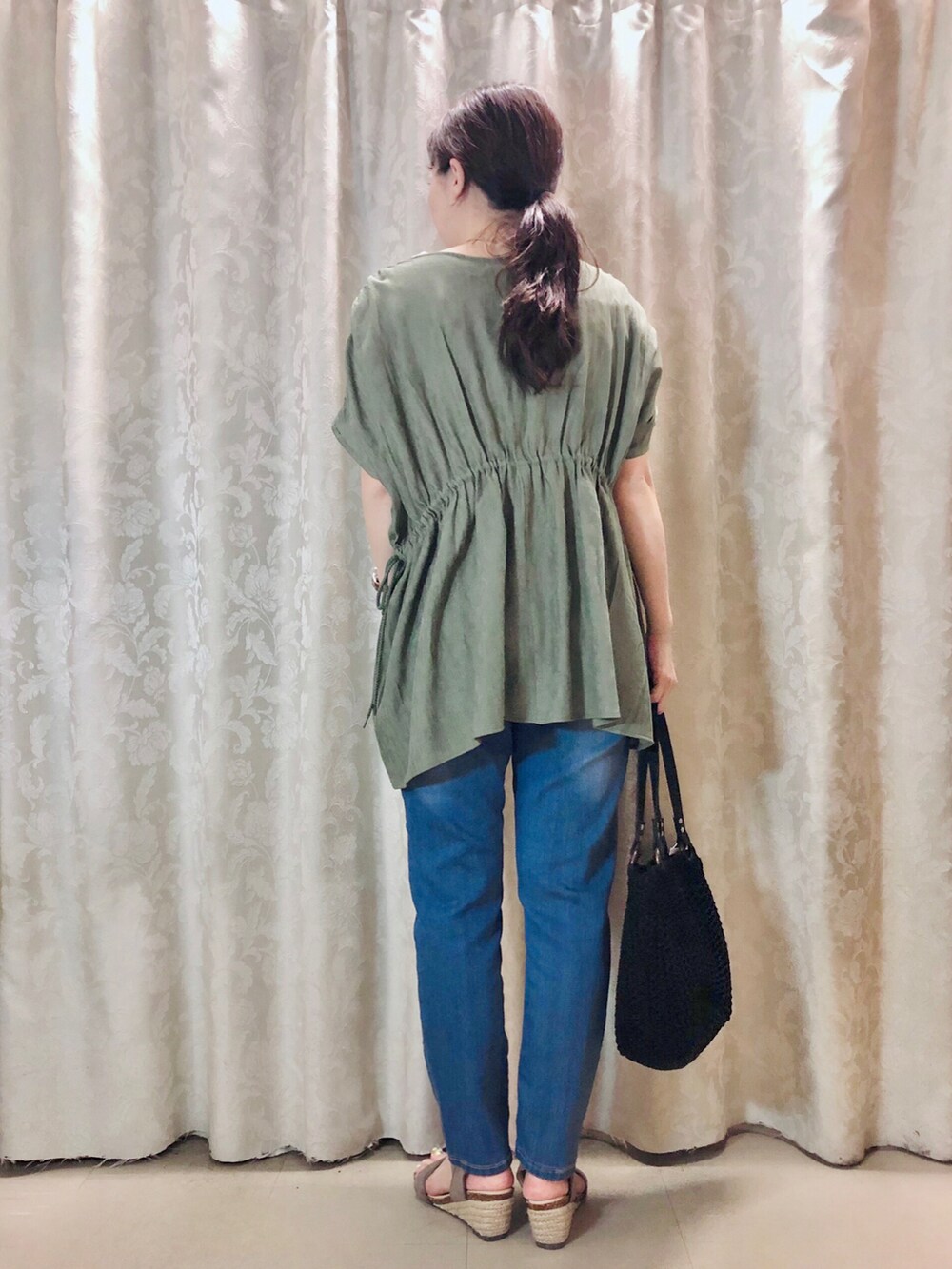 グリーン系のシャツ/ブラウス、ブラウン系のサンダル、ブルー系のデニムパンツを着用したレディースの春コーディネートの3枚目の写真