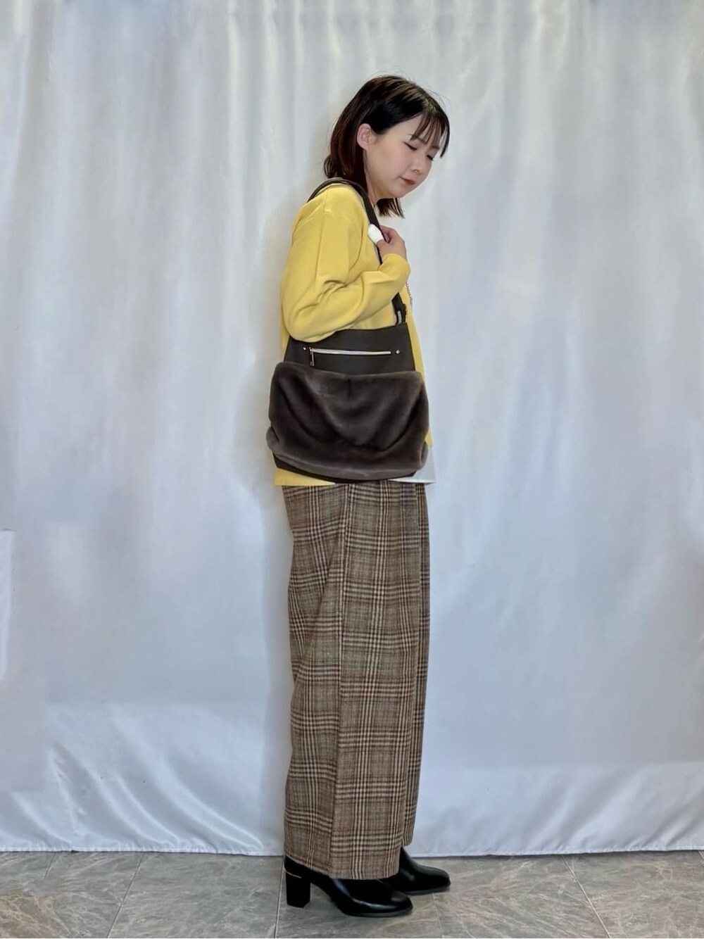 イエロー系のニット/セーター、ブラウン系のその他パンツ、ブラック系のブーツを着用したレディースの冬コーディネートの2枚目の写真