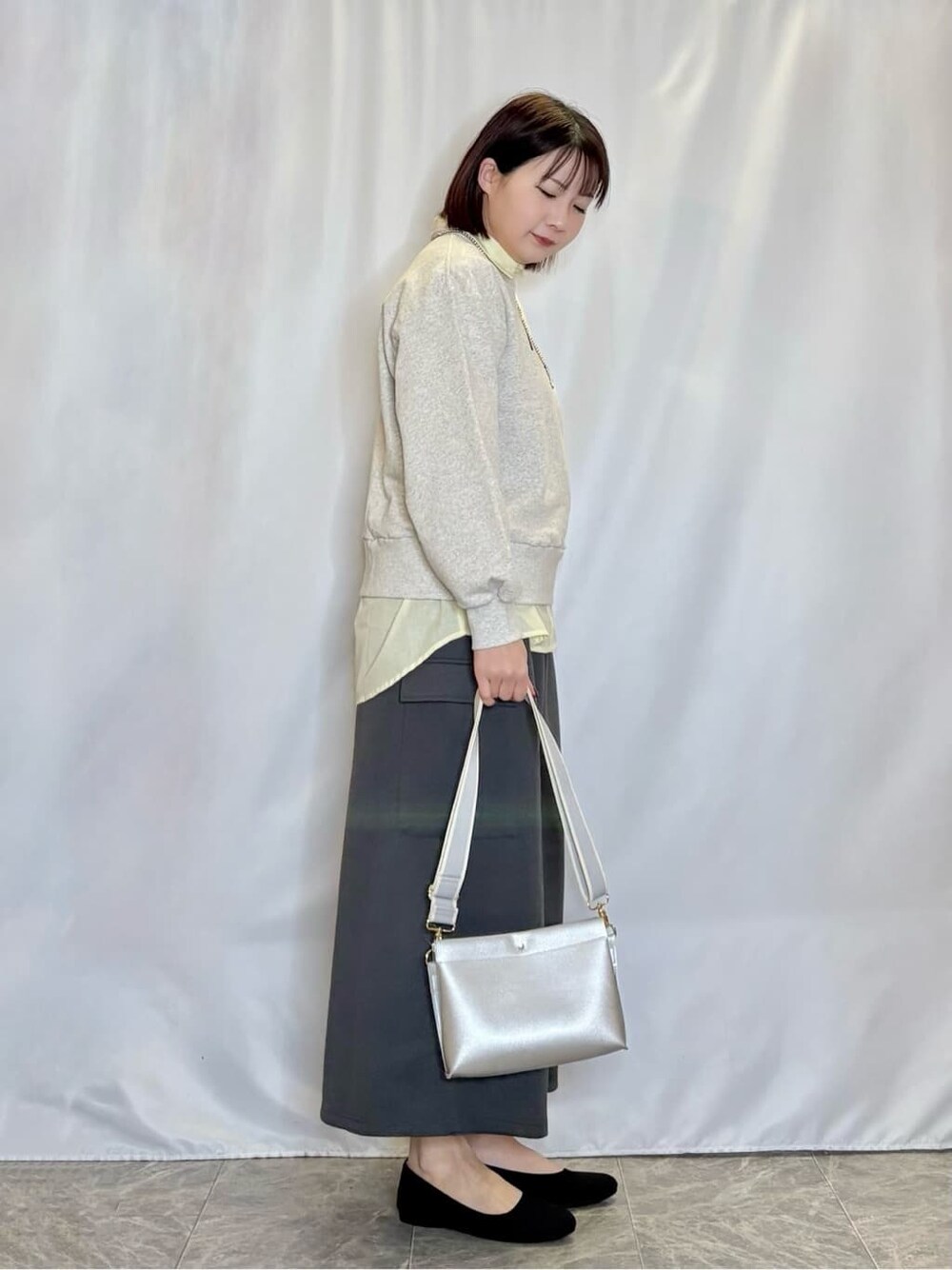 グレー系のスウェット、イエロー系のシャツ/ブラウス、グレー系のスカートを着用したレディースの冬コーディネートの2枚目の写真