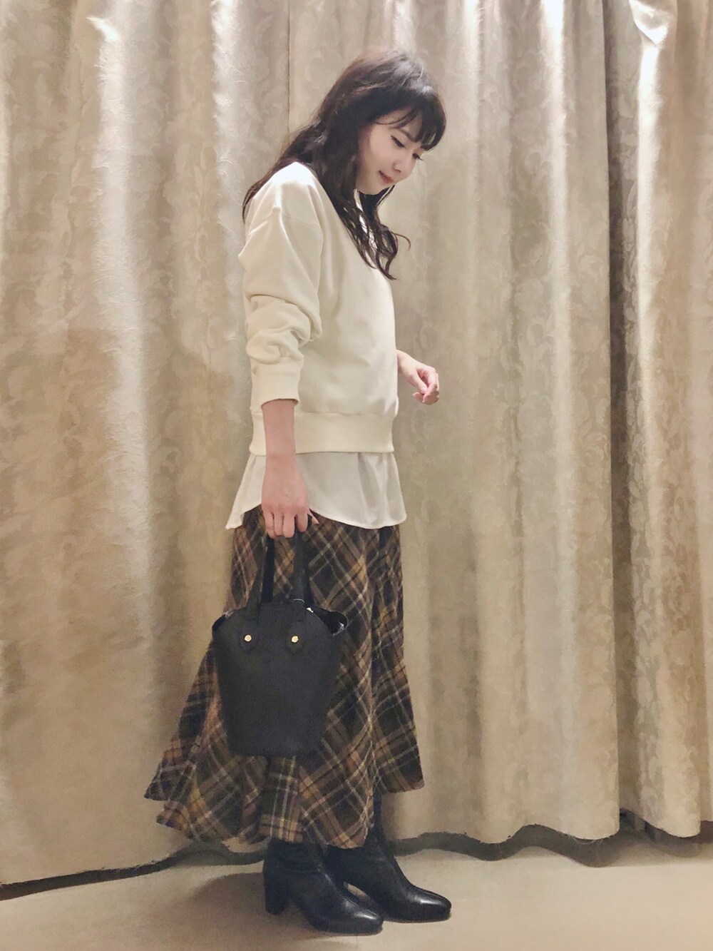 ブラック系のトートバッグ、ブラック系のブーツ、イエロー系のスカートを着用したレディースの秋コーディネートの2枚目の写真