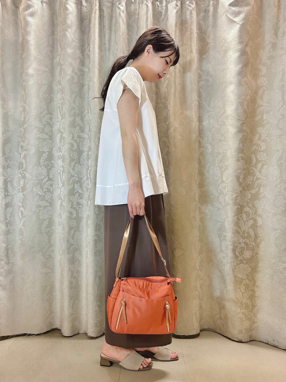ベージュ系のサンダル、オレンジ系のショルダーバッグ、ホワイト系のTシャツ/カットソーを着用したレディースの春コーディネートの2枚目の写真
