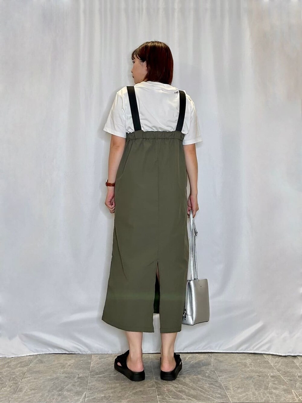 グリーン系のワンピース、ホワイト系のTシャツ/カットソー、ブラック系のサンダルを着用したレディースの夏コーディネートの3枚目の写真