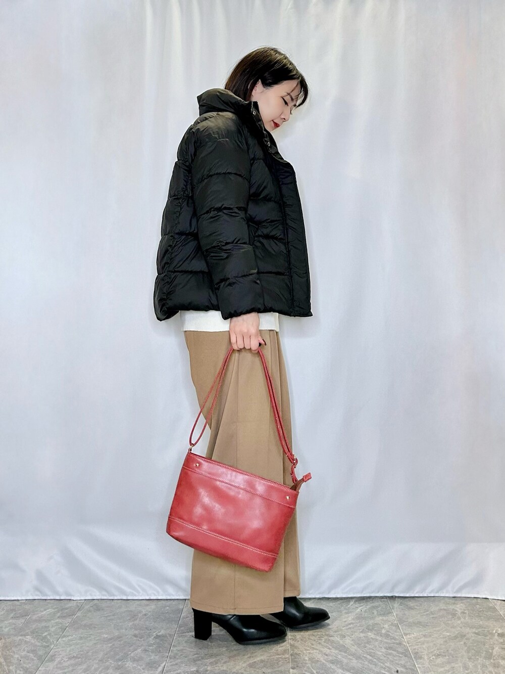 ブラック系のブーツ、レッド系のショルダーバッグ、イエロー系のその他パンツを着用したレディースの冬コーディネートの2枚目の写真