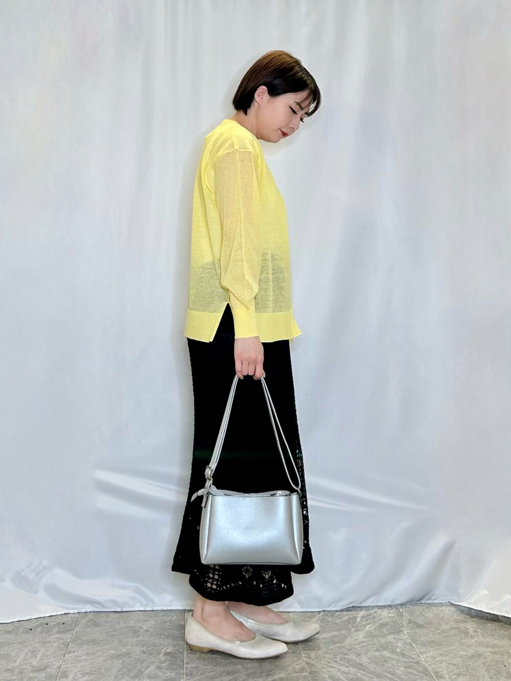 ブラック系のスカート、ゴールド系のその他シューズ、シルバー系のショルダーバッグを着用したレディースの春コーディネートの2枚目の写真
