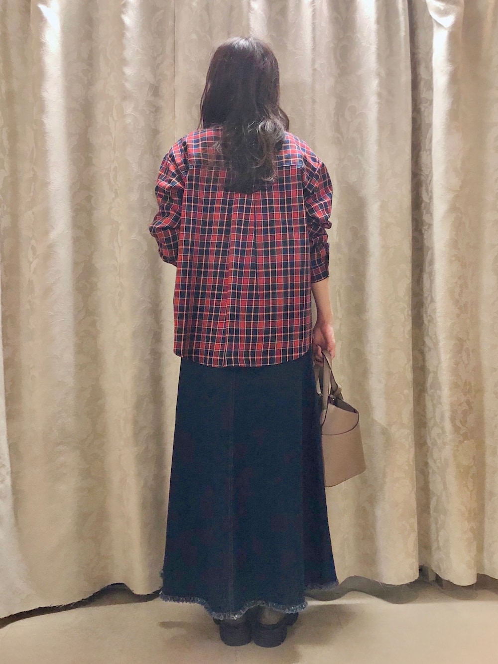 ベージュ系のトートバッグ、ブラウン系のブーツ、ブルー系のデニムスカートを着用したレディースの秋コーディネートの3枚目の写真