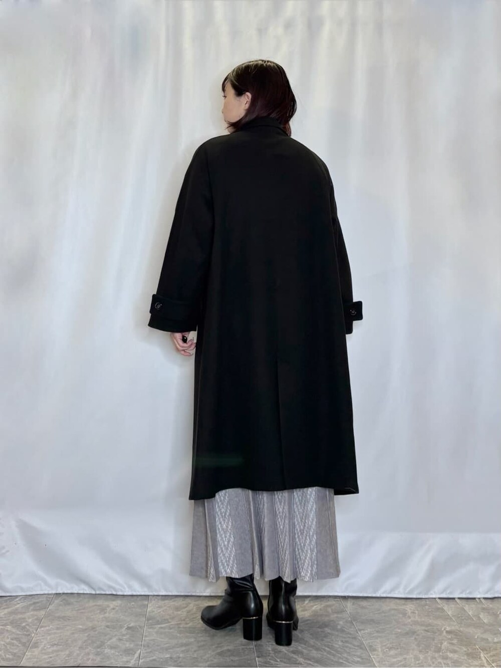 ブラック系のその他アウター、グレー系のニット/セーター、グレー系のスカートを着用したレディースの冬コーディネートの3枚目の写真