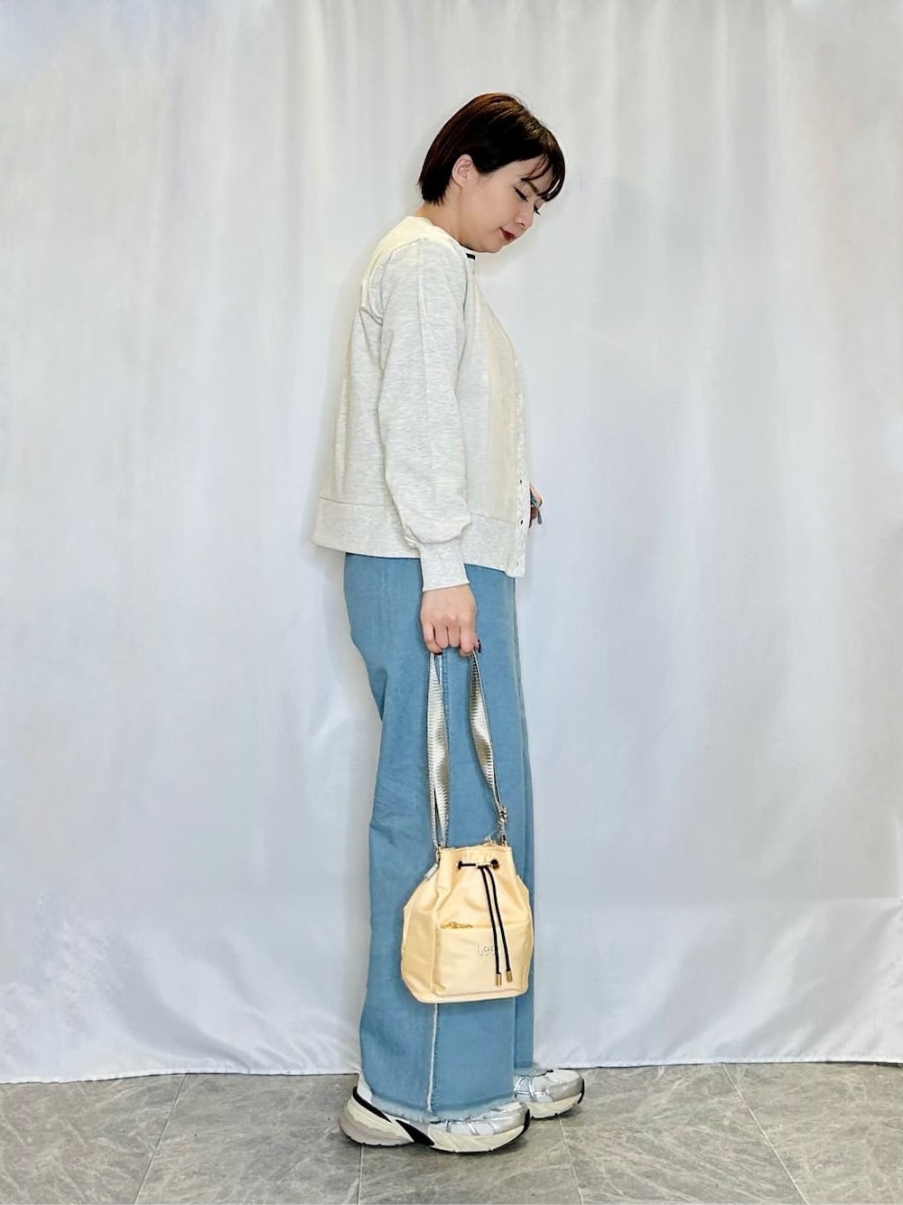 グレー系のカーディガン/ボレロ、ホワイト系のTシャツ/カットソー、ブルー系のデニムパンツを着用したレディースの春コーディネートの2枚目の写真