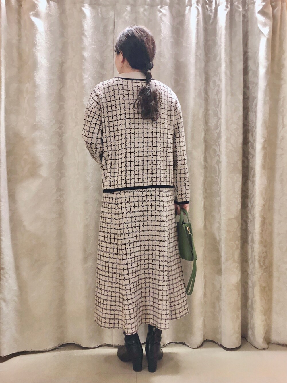 ブラック系のブーツ、グリーン系のショルダーバッグ、ベージュ系のスカートを着用したレディースの冬コーディネートの3枚目の写真