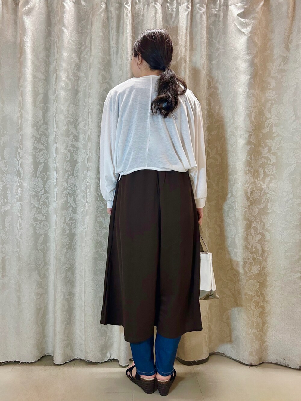 ホワイト系のカーディガン/ボレロ、ブラウン系のワンピース、ブラック系のサンダルを着用したレディースの春コーディネートの3枚目の写真