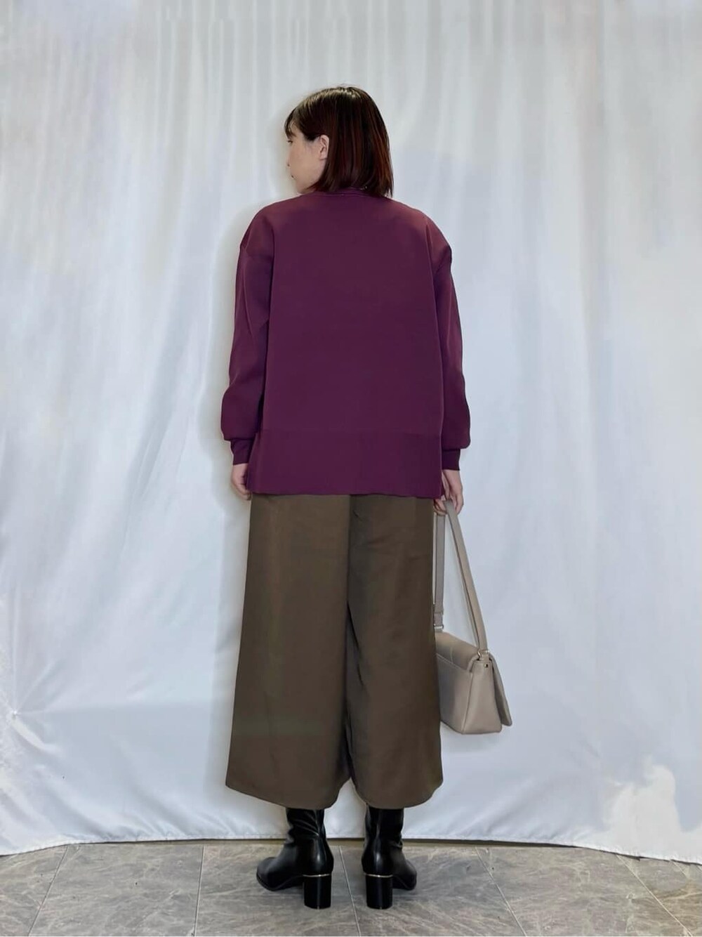 パープル系のニット/セーター、ブラウン系のその他パンツ、ブラック系のブーツを着用したレディースの秋コーディネートの3枚目の写真