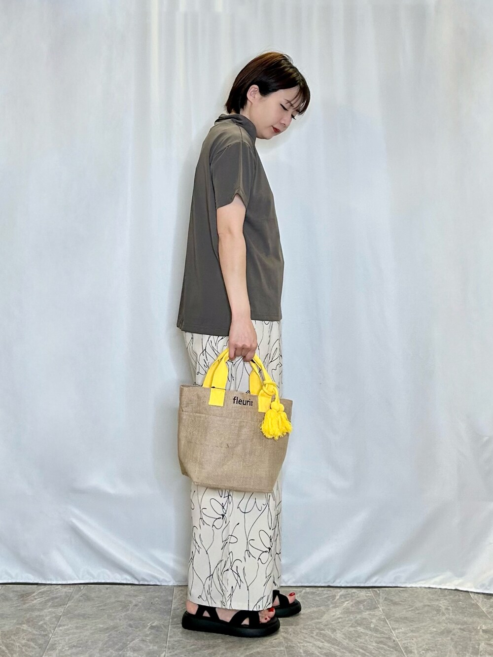 ホワイト系のその他パンツ、ブラック系のサンダル、イエロー系のトートバッグを着用したレディースの春コーディネートの2枚目の写真