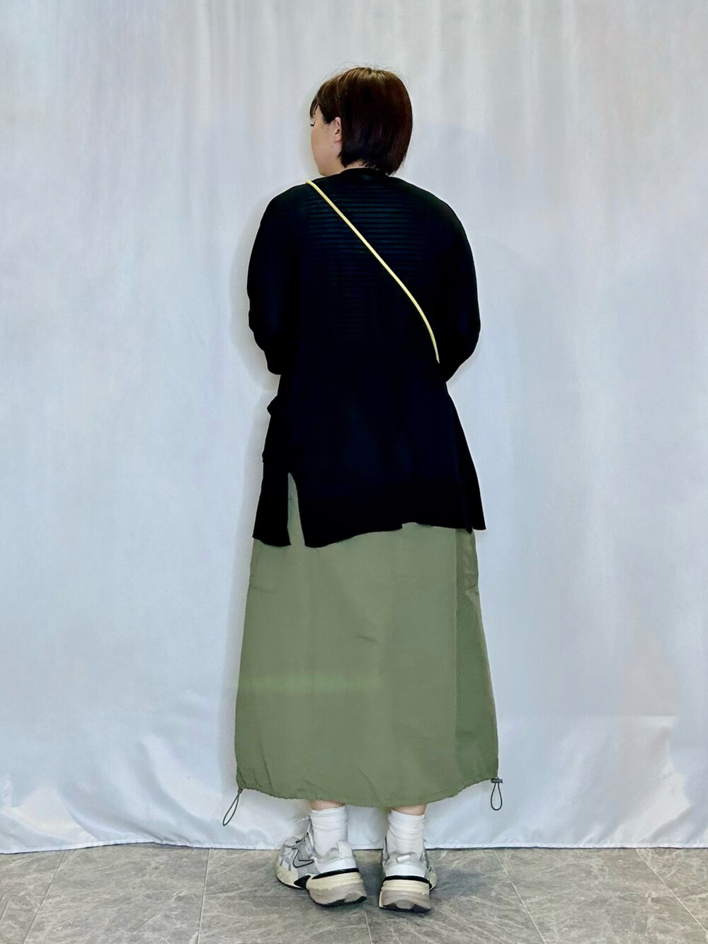 グリーン系のスカート、イエロー系のショルダーバッグ、ブラック系のカーディガン/ボレロを着用したレディースの春コーディネートの3枚目の写真