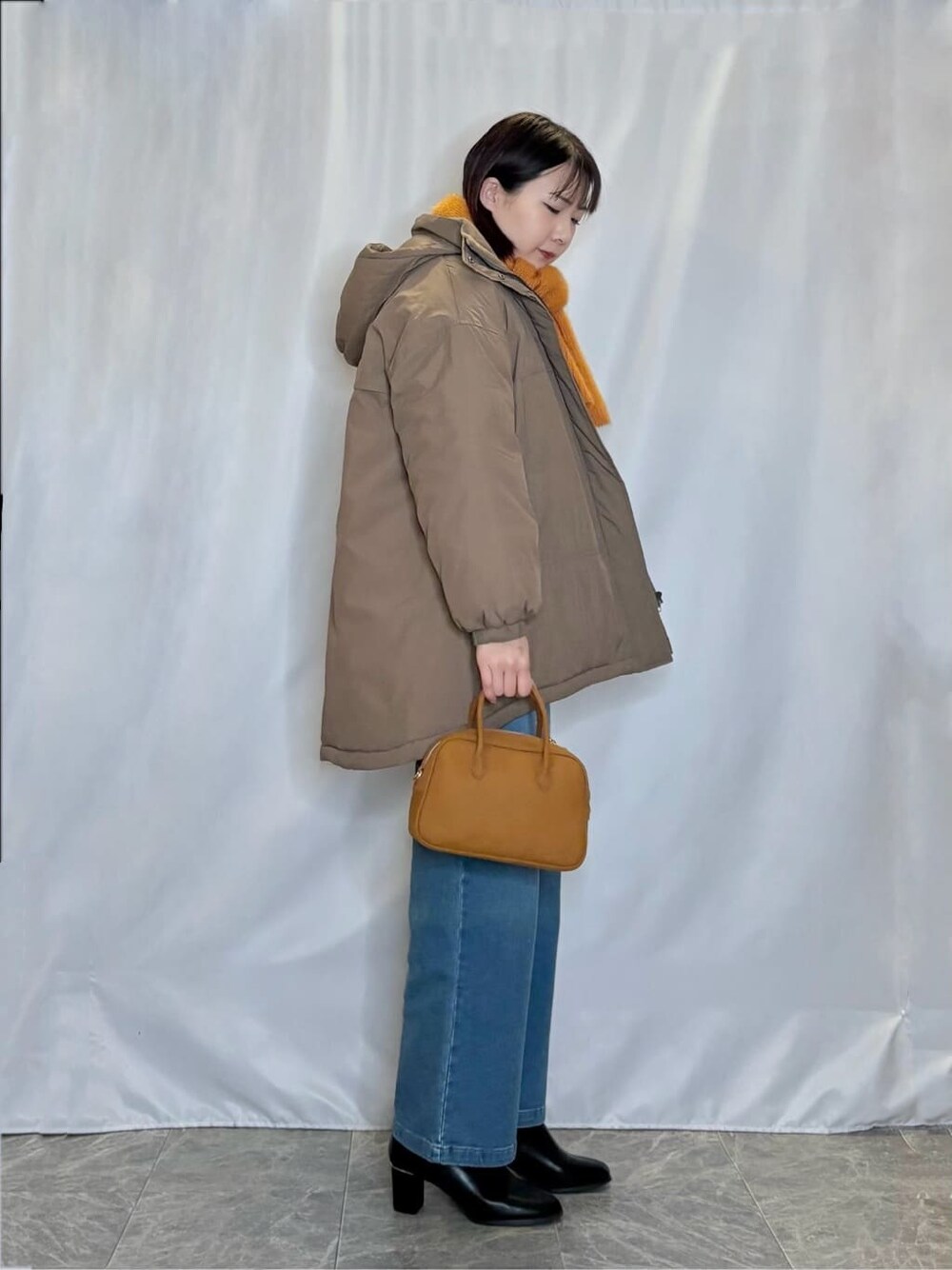 ブラウン系のその他アウター、ホワイト系のニット/セーター、ブルー系のデニムパンツを着用したレディースの冬コーディネートの2枚目の写真