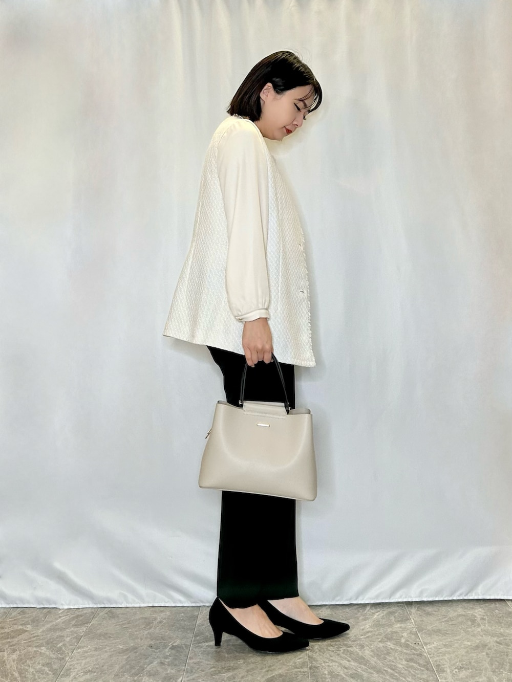 ブラック系のパンプス、ブラック系のその他パンツ、ベージュ系のトートバッグを着用したレディースの冬コーディネートの2枚目の写真